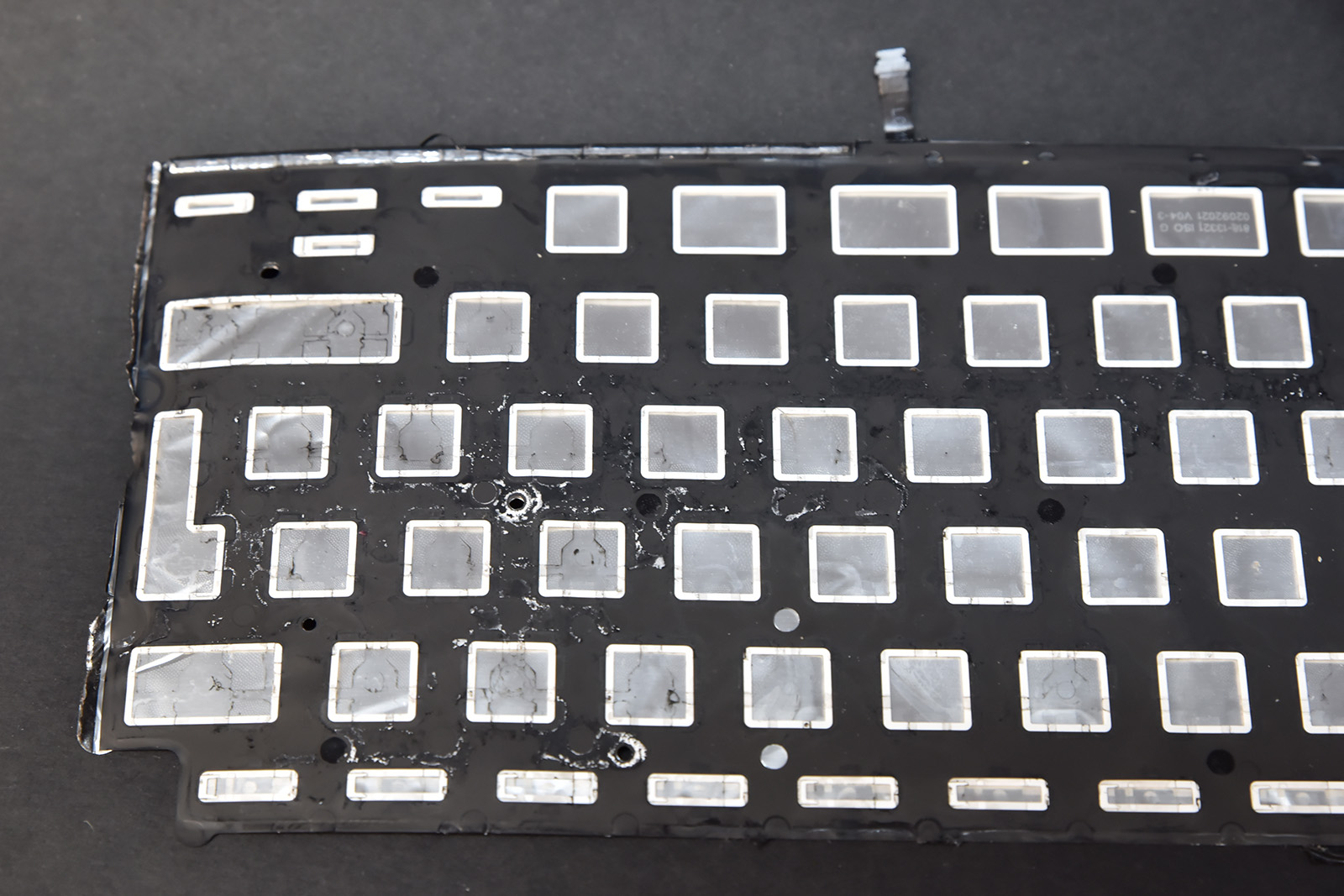 Membrana klawiatury laptopa po zalaniu – widoczne ślady cieczy powodujące brak reakcji klawiszy