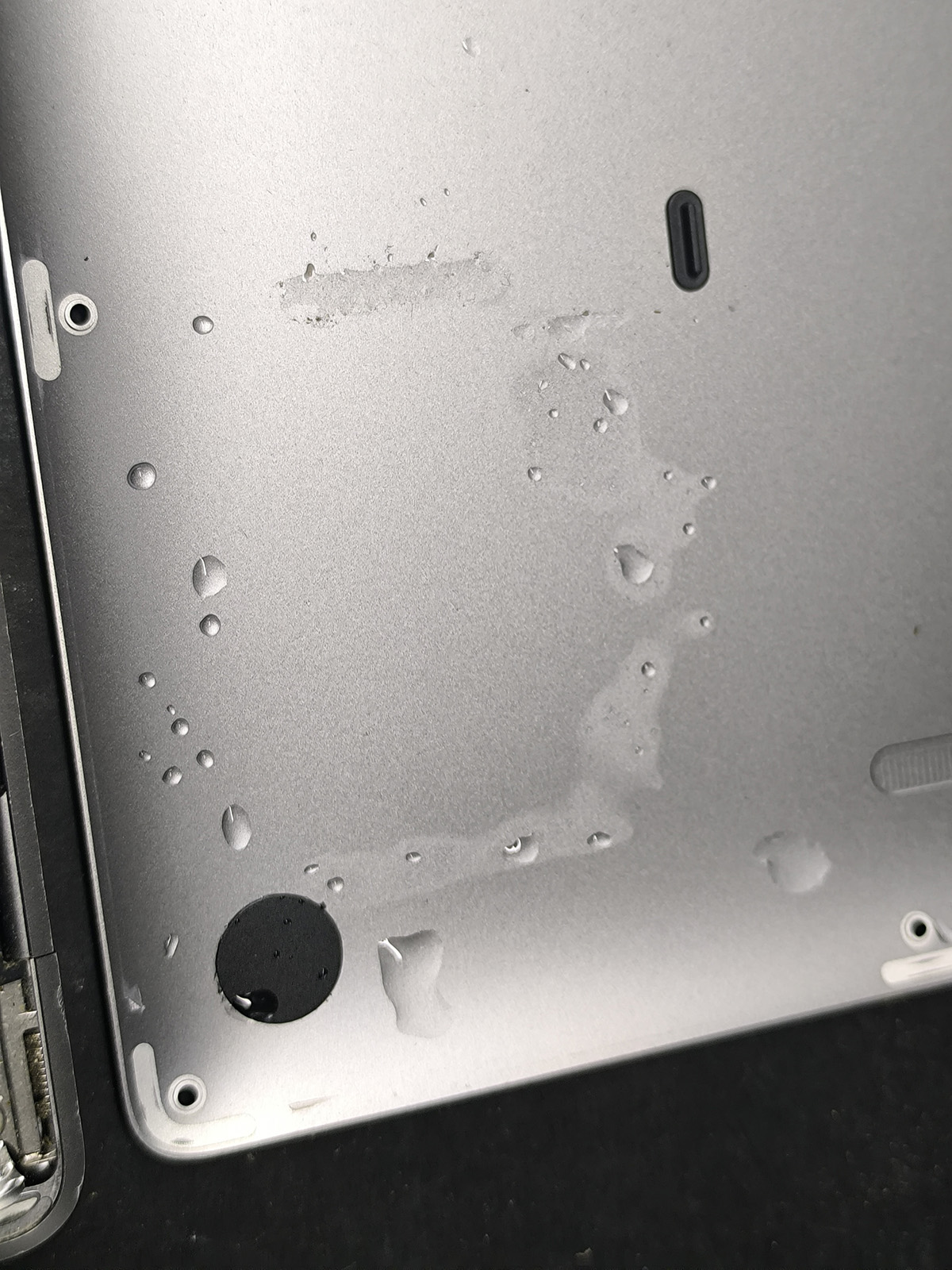 Ślady wody na dolnej pokrywie MacBooka Air A2337 po zalaniu