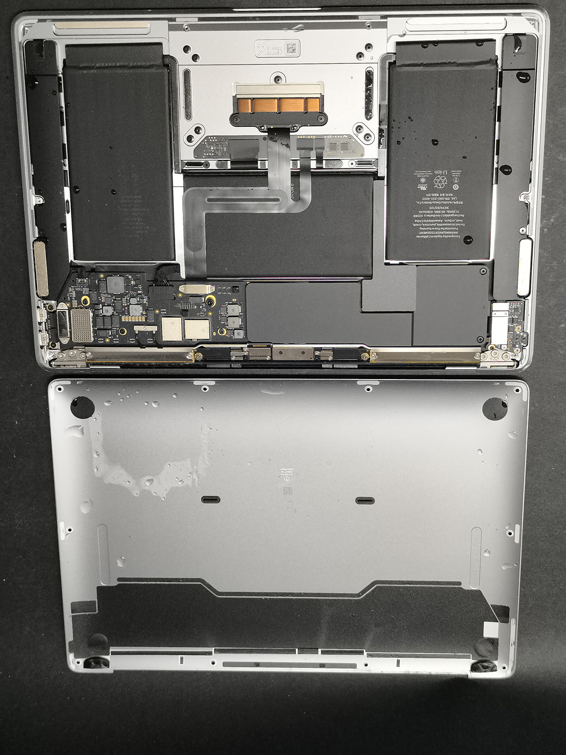 Otwarty zalany MacBook z kroplami cieczy widocznymi wewnątrz obudowy